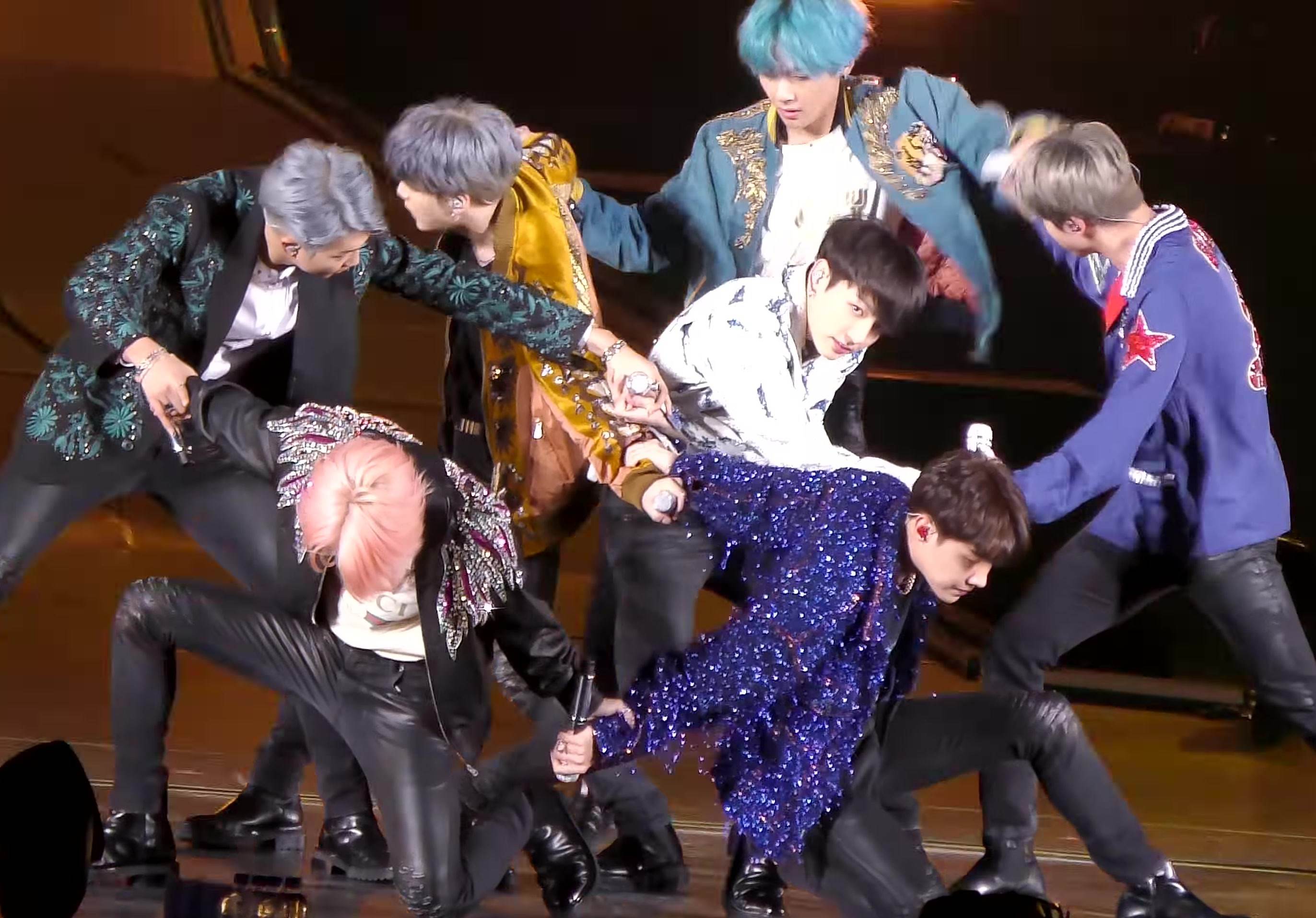 BTS on stage together in sequinned jackets during a concert