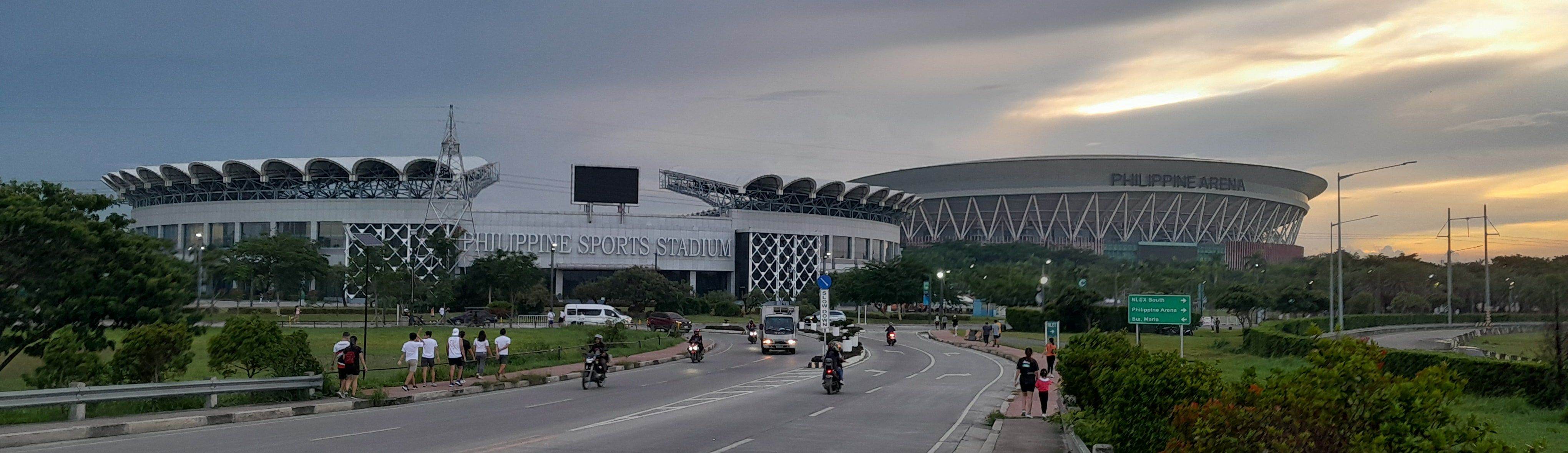 The Philippine Sports Stadium and the Philippine Arena at dawn, seen from the road into Ciudad de Victoria