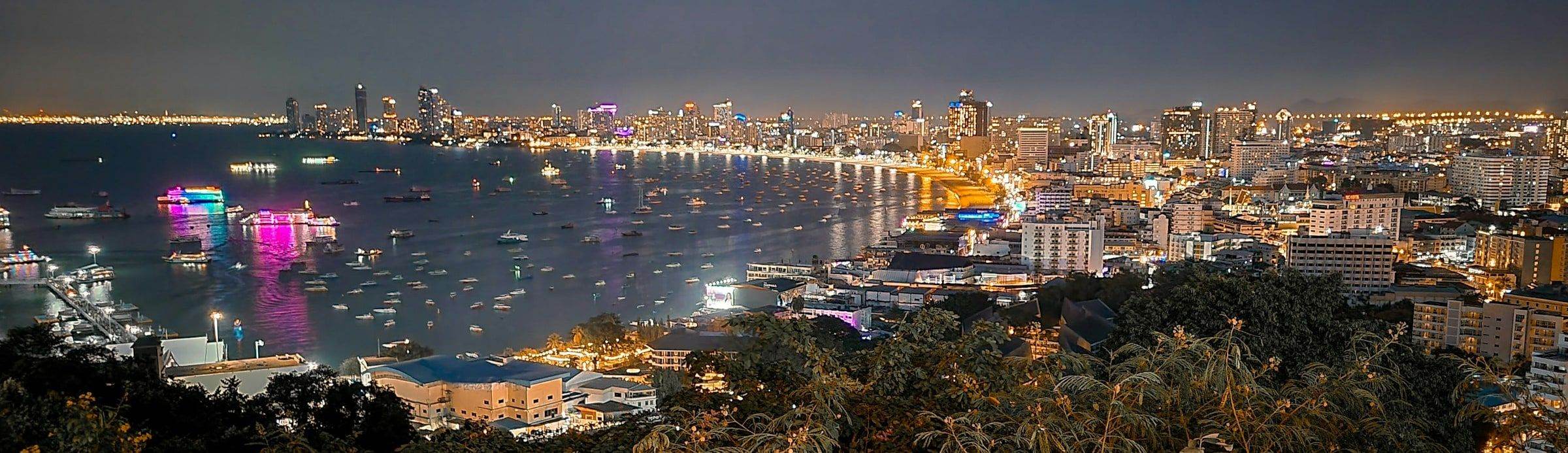 Pattaya bay at night, lit boats on the water and the city along the shore