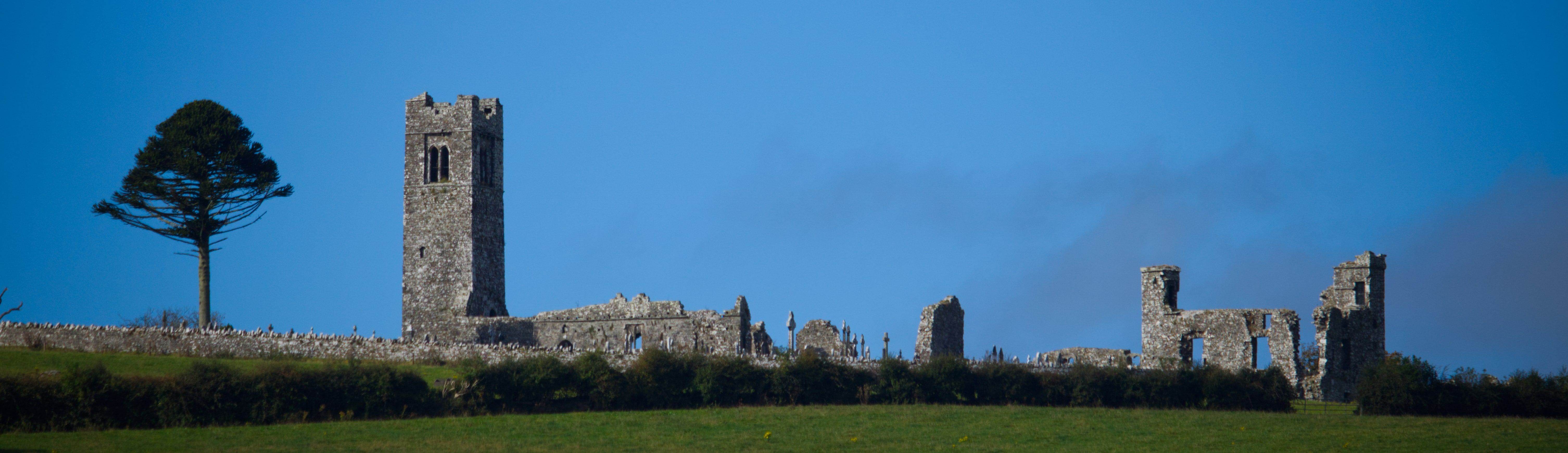 The ruined abbey tower and walls on the Hill of Slane against a deep blue sky